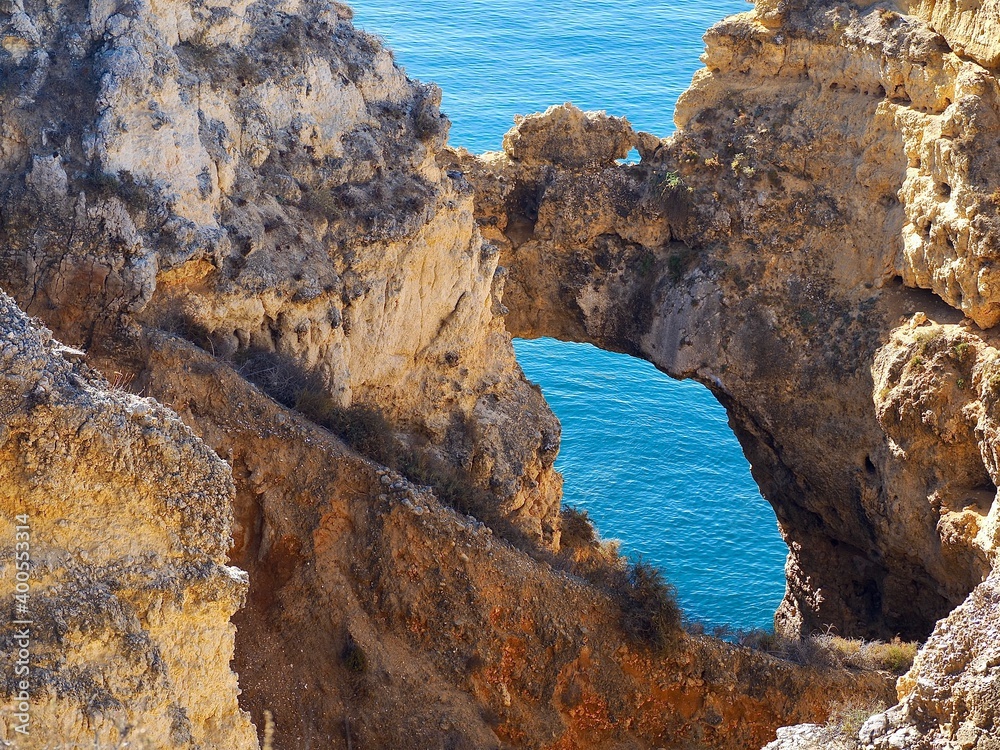 The beauty of Portugal - hiking in Lagos in Portugal - a gate in the cliffs with view on the blue Atlanti ocean