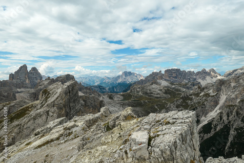 An endless view on a high and desolated mountain peaks in Italian Dolomites. The lower parts of the mountains are overgrown with moss and grass. Raw and unspoiled landscape. Few clouds above the peaks © Chris