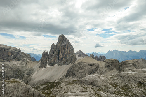 An endless view on a high and desolated mountain peaks in Italian Dolomites. The lower parts of the mountains are overgrown with moss and grass. Raw and unspoiled landscape. Few clouds above the peaks