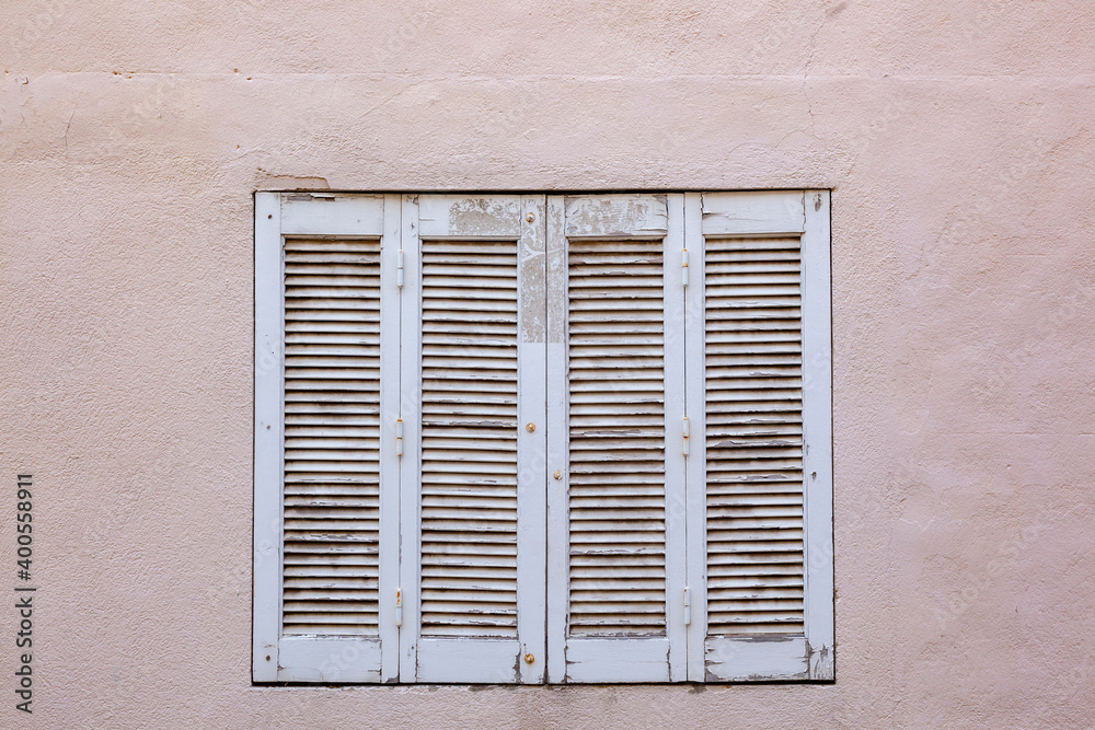 old house with wooden window shutter and peeling paint
