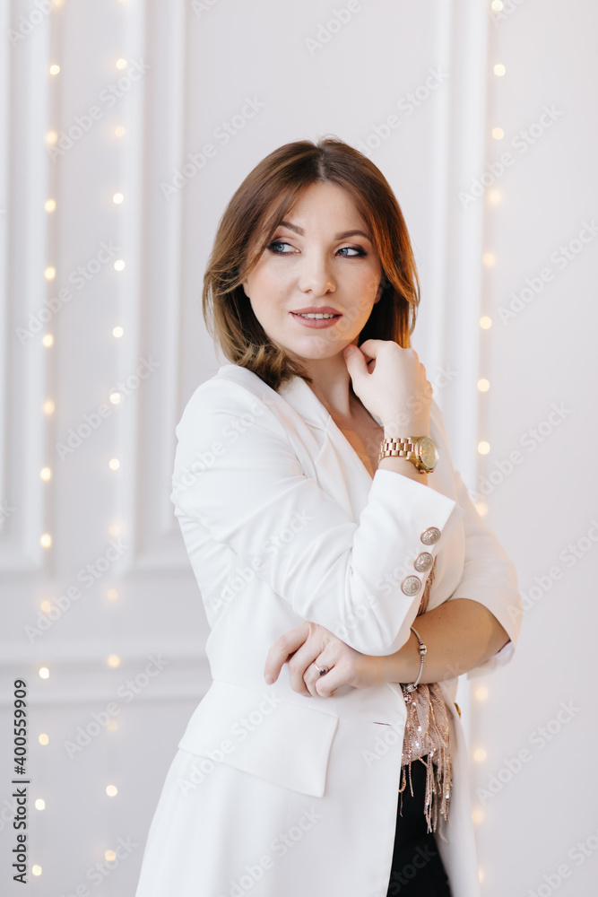 Business fashion woman in a classic suit with white jacket, black pants and high heels on white wall with light background Business fashion woman in a classic suit with white jacket, black pants and high heels on white wall with light background