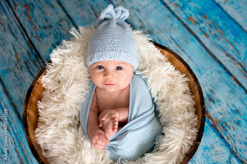 Little baby boy with knitted hat in a basket, happily smiling