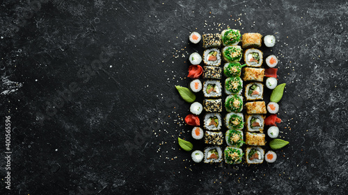 Set of tasty sushi and maki rolls on black stone background. Japanese food. Top view. Free space for your text