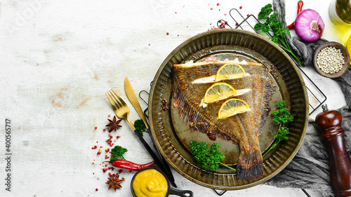 Baked flounder fish with lemon and spices on a metal baking dish. Seafood. Top view. Free space for text.