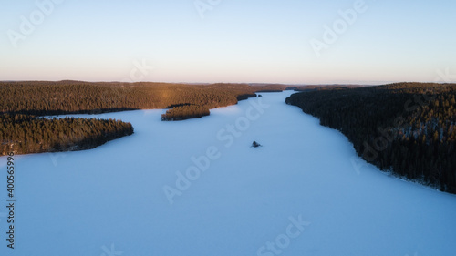 Aerial view of a white snowy lake and islands in winter on a sunny day  against a blue sky.