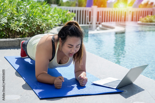 Fat Asian Women Training Yoga  and plank With Laptop Application At The Pool To Lose Weight.Sport and health concept. photo