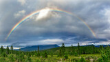 rainbow over mountains and forest on a cloudy summer day