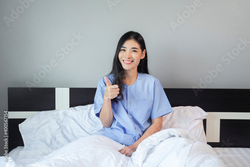 Asian woman happy patient resting in bed at hospital private room with illness disease unhealthy, panic patient in medical health care insurance, happy cheerful joyful thumbs up feeling ok and healthy