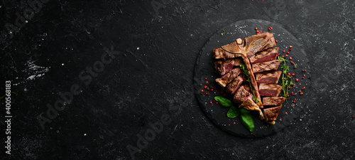 Juicy grilled steak from Angus with spices and herbs on a black background. Bull Angus. Top view. Rustic style.