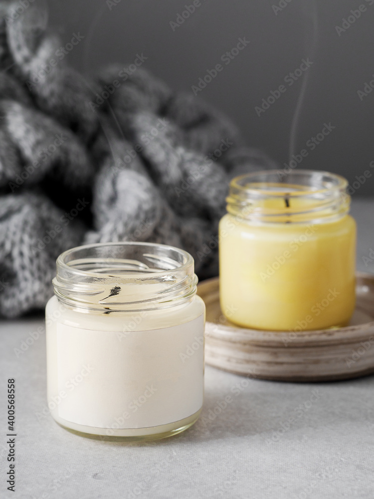Burning candles on grey table, space for text. Grey knitted scarf and scented candles. Cozy winter atmosphere. 2021. Сolors of the year. burning candles on a gray background. New Year. Romantic. Burning candles on grey table, space for text. Grey knitted scarf and scented candles. Cozy winter atmosphere. 2021. Сolors of the year. burning candles on a gray background. New Year. Romantic.
