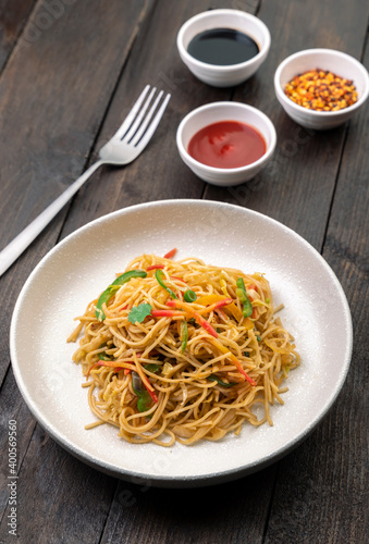 stir fried vegetarian noodles with sauce served in a white plate with fork