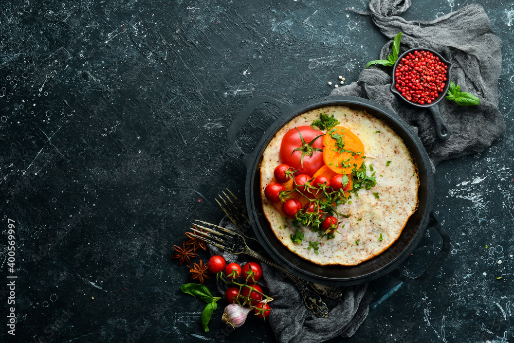 Omelet with tomatoes and parsley in a pan. Food for breakfast. Free space for your text. Top view. Omelet with tomatoes and parsley in a pan. Food for breakfast. Free space for your text. Top view.