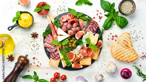 A plate with cheese, salami, prosciutto and snacks on a black stone plate. Antipasto. Top view. Italian food. Free space for your text.