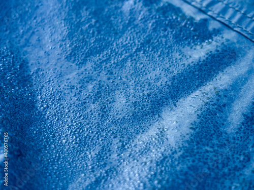 Water drops on waterproof membrane fabric. Detail view of texture of blue synthetic waterproof cloth. Morning dew on tent.