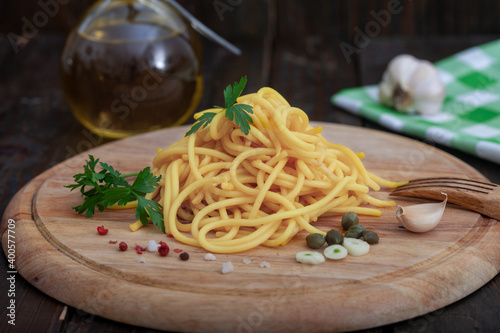 Simple italian spaghetti with olive oil and ingredients on wooden board. Healthy vegetarian pasta food.