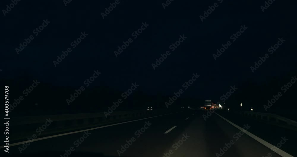 Driving Car on Highway at Night. Vehicle Overtakes Cargo Truck. SUV Windshield Hood POV. Heavy Traffic