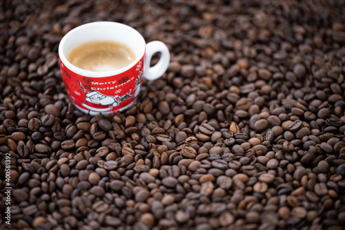 Flat lay with copy space, (selective focus) A Christmas cup with some creamy coffee is placed on some roasted coffee beans.
