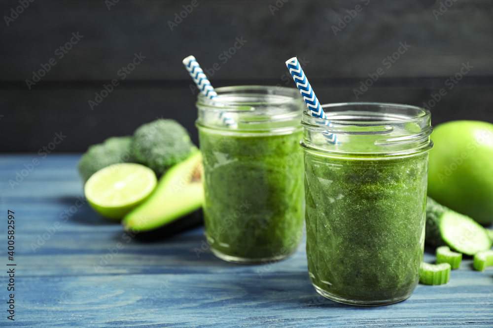 Delicious fresh green juice on blue wooden table. Space for text