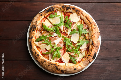 Tasty pizza with meat and arugula on wooden table, top view