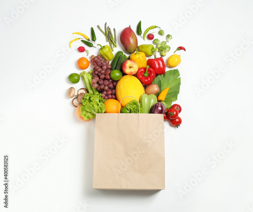 Paper bag with assortment of fresh organic fruits and vegetables on white background  top view