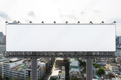 Blank white road billboard with Bangkok cityscape background at day time. Street advertising poster, mock up, 3D rendering. Front view. The concept of marketing communication to promote or sell idea.