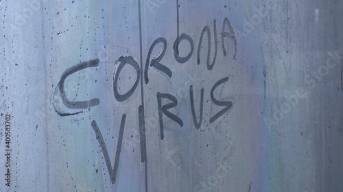 written Covid-19 Coronavirus on a fogged glass - hand erases the writing - concept of the end of the pandemic thanks to the arrival of the vaccine