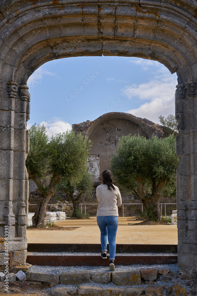 Caucasian woman traveler in Montemor o Novo stone castle ruin entrance gate of old church in Alentejo, Portugal