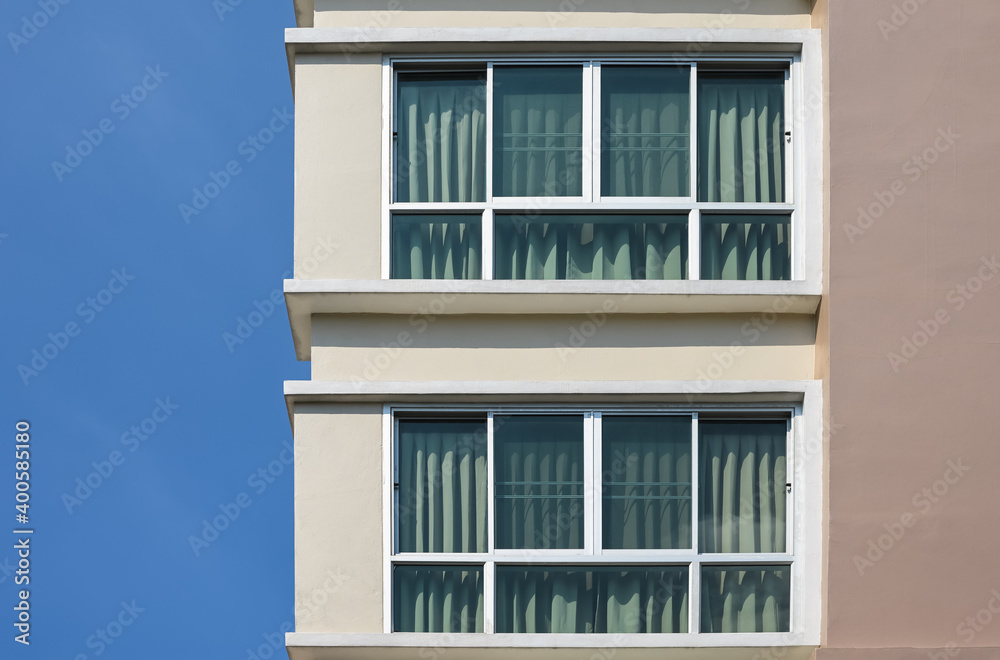 Modern building against a clear blue sky. Two glass windows with curtain..