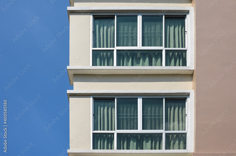 Fototapeta premium Modern building against a clear blue sky. Two glass windows with curtain..