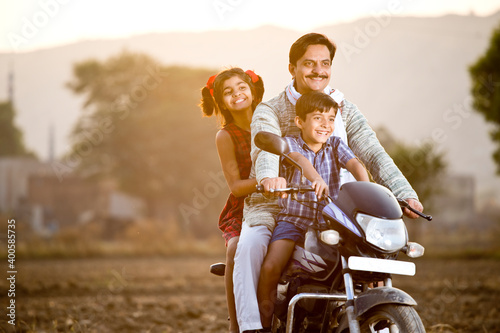Happy rural Indian farmer with children riding on motorcycle