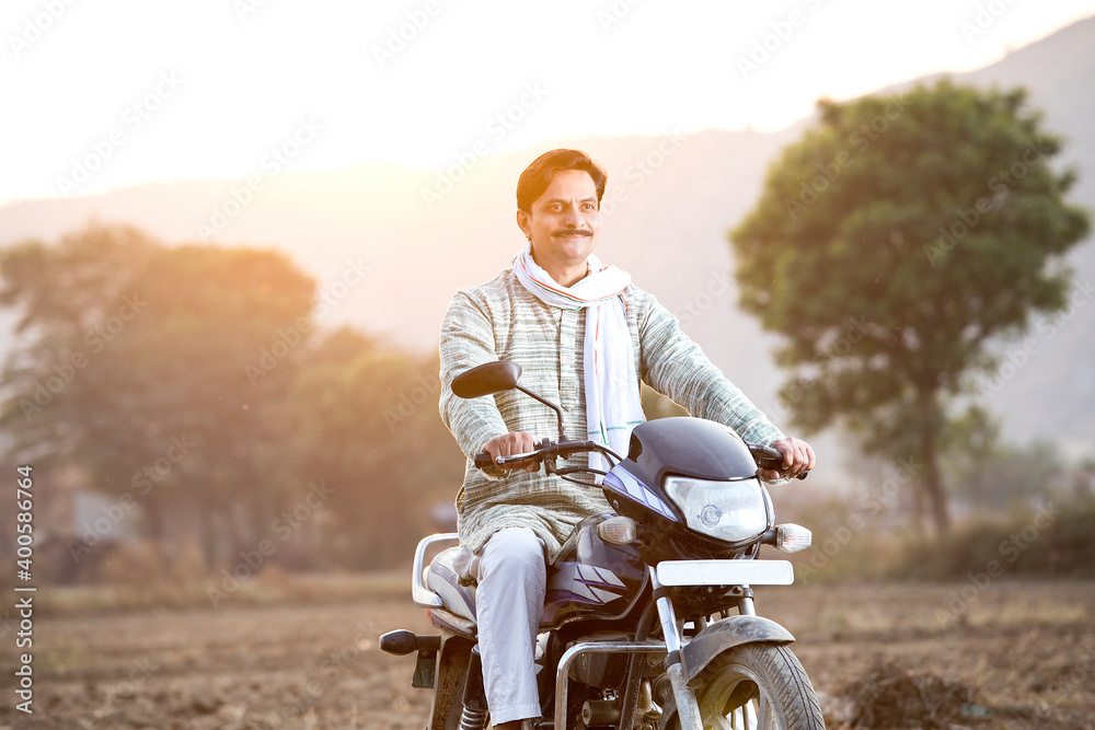 Happy rural Indian man riding on motorcycle in village
