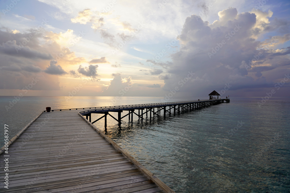 Long wooden pier over the water, at sunset, Maldives 