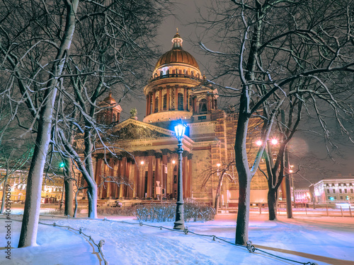 Winter evening in Saint-Petersburg. Cities of Russia. Lantern at St. Isaac Cathedral is lit. St. Isaac's Cathedral with evening illumination. Petersburg cathedrals. St. Isaac square under the snow.