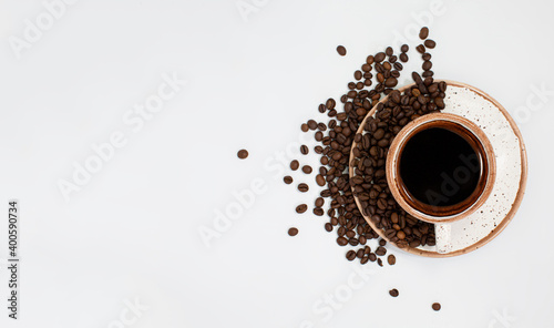 a coffee cup with roasted brown beans is scattered on a white table with plenty of room for text. Composition Of a flat layer. Close-up, top view, white background.