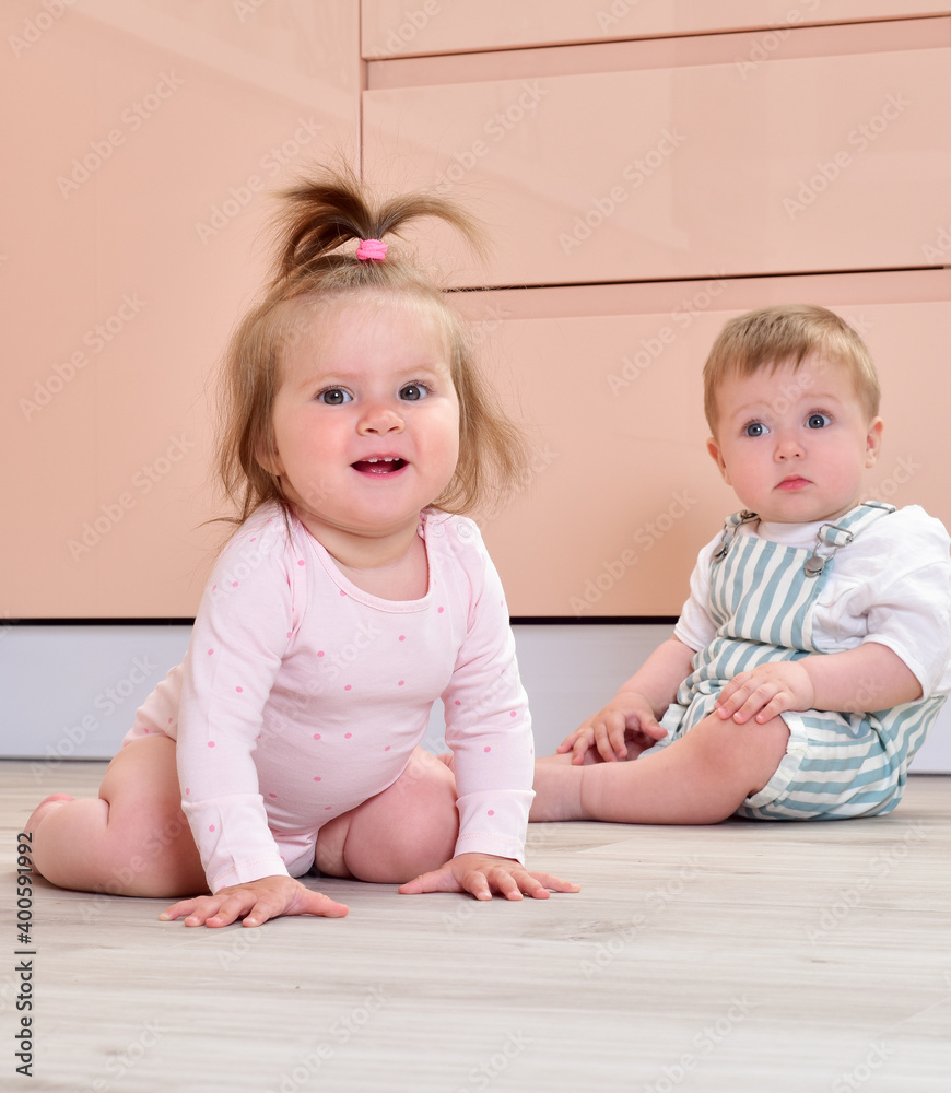 Beautiful babies in the interior. Baby on the floor in the kitchen interior. Two lovely kids, sitting on the floor. Beautiful babies in the interior. Baby on the floor in the kitchen interior. Two lovely kids, sitting on the floor.