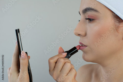 Beautiful woman applying makeup on her lips