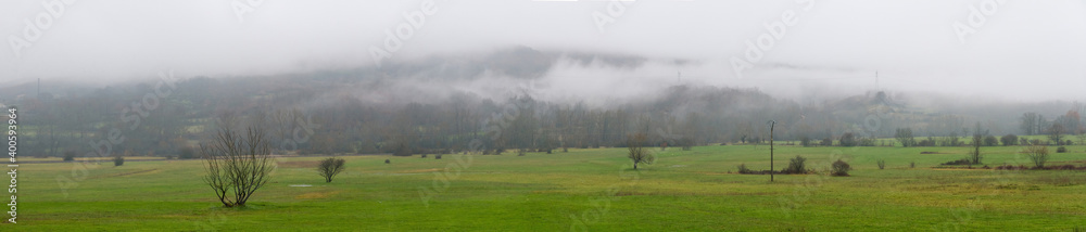 Winter Landscape Meadow and mountain in the background with low clouds 