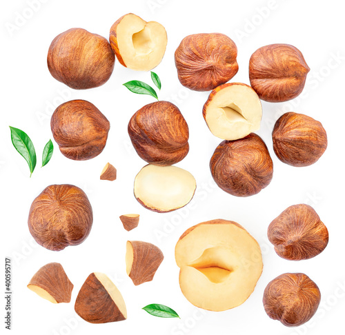 Hazelnuts whole and crushed pieces with  green leaves isolated  on a white background. Creative food layout. Pattern with hazel nuts. photo