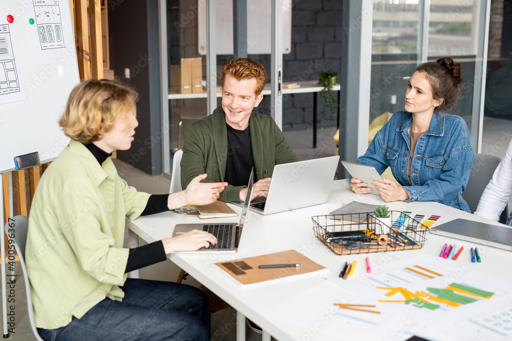 Obraz premium Happy young male mobile app developer looking at one of his female colleagues