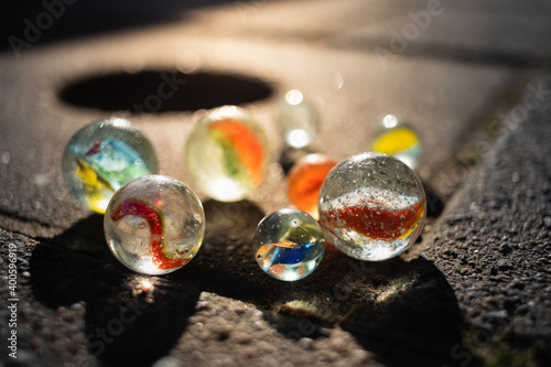 A group of marbles on the sidewalk near a marble pot illuminated by golden sun rays. photo