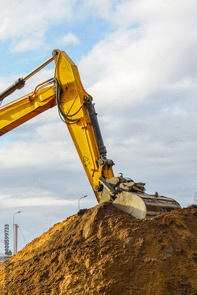 a yellow excavator boom with a bucket digs a pile of earth a yellow excavator boom with a bucket digs a pile of earth