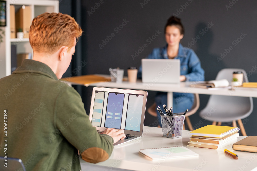 Young male software developer looking at electronic sketches of new mobile app