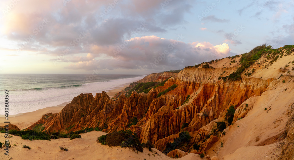 bizarre eroded sand dunes on the Atlantic Ocean with waves rolling in at sunset