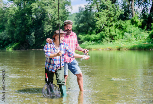 Rod tackle. Fishing equipment. Hobby sport. Fishing peaceful activity. Father and son fishing. Grandpa and mature man friends. Fishing with spinning reel. Sunny summer day at river. Fisherman family