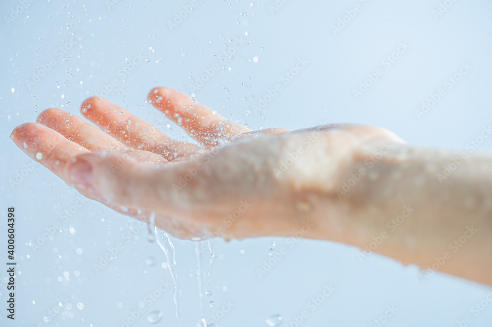 A woman's hand in the contour light with water drops of pure water. Moisturizing or skin care, clean and fresh.
