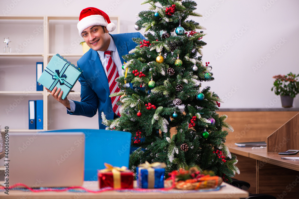 Young male employee celebrating Christmas at workplace Young male employee celebrating Christmas at workplace