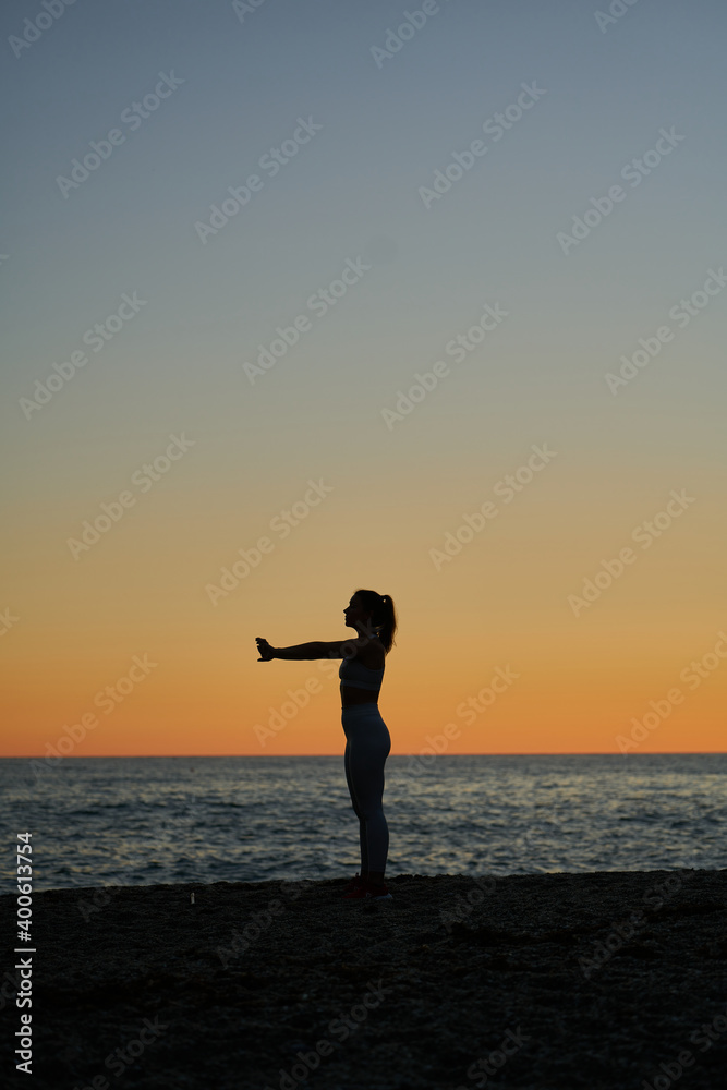 young spanish girl doing exercise in front of the mediterranean sea at sunset