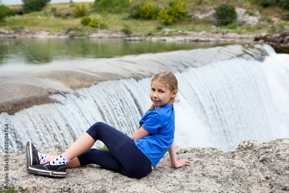 Portrait of pre-teen girl resting close to waterfall of the Cijevna river. It is called Montenegrin Niagara Falls. Surroundings of Podgorica city. Montenegro, Europe