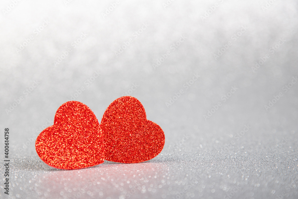 Fototapeta premium two red hearts in glitter on a silver glitter background
