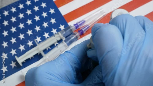 bottle a vaccine is held by hand in a glove on background of the USA flag, vaccine against coronavirus, Operation Warp Speed photo